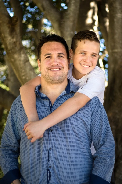 a man holding a young boy in his arms, a picture, by Matt Stewart, avatar image, manuka, headshot photo, teenager