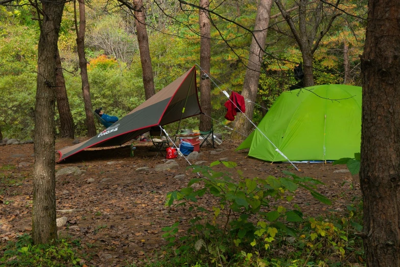 a green tent sitting in the middle of a forest, a picture, by Richard Carline, shutterstock, in karuizawa, front and side view, green and red, mid fall