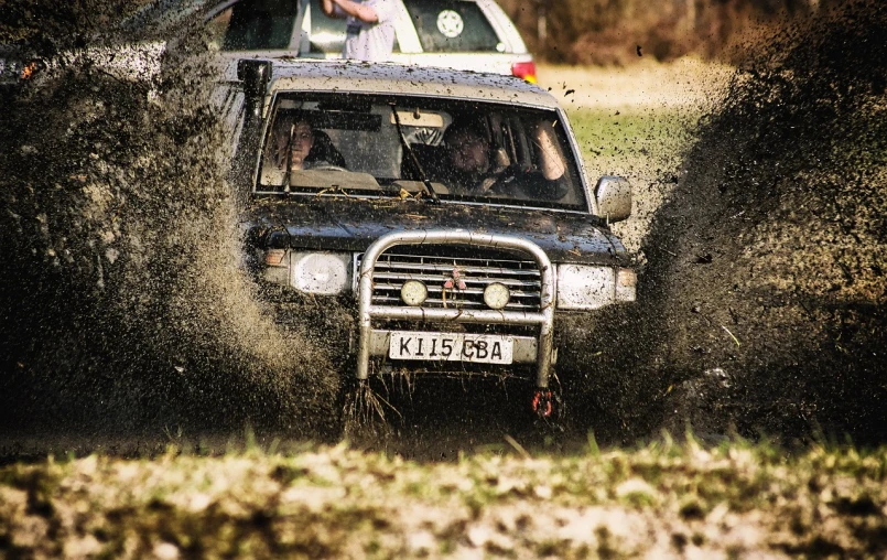 a couple of people riding in the back of a truck, by Richard Carline, flickr, flying mud, battle action shot, 50mm photo, full car