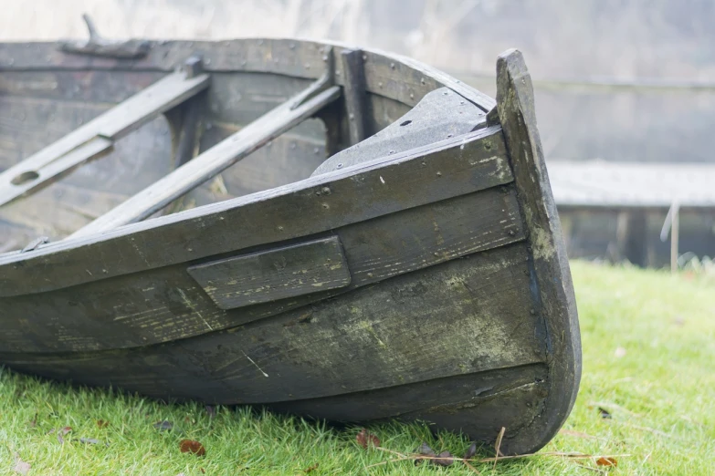 a wooden boat sitting on top of a lush green field, a picture, by Richard Carline, shutterstock, photo of poor condition, replica model, side view close up of a gaunt, stock photo