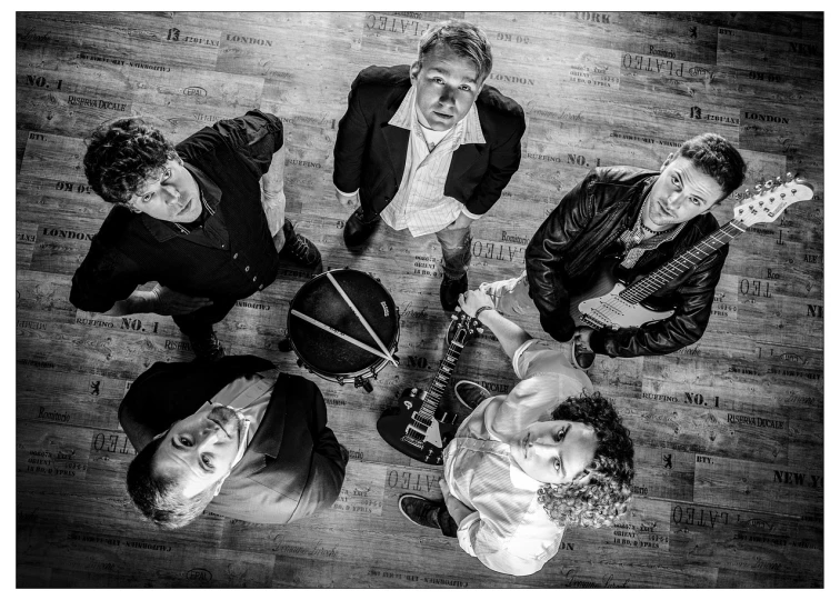 a group of people standing on top of a wooden floor, a portrait, by Colijn de Coter, flickr, band playing instruments, monochrome:-2, air shot, vivid bright light