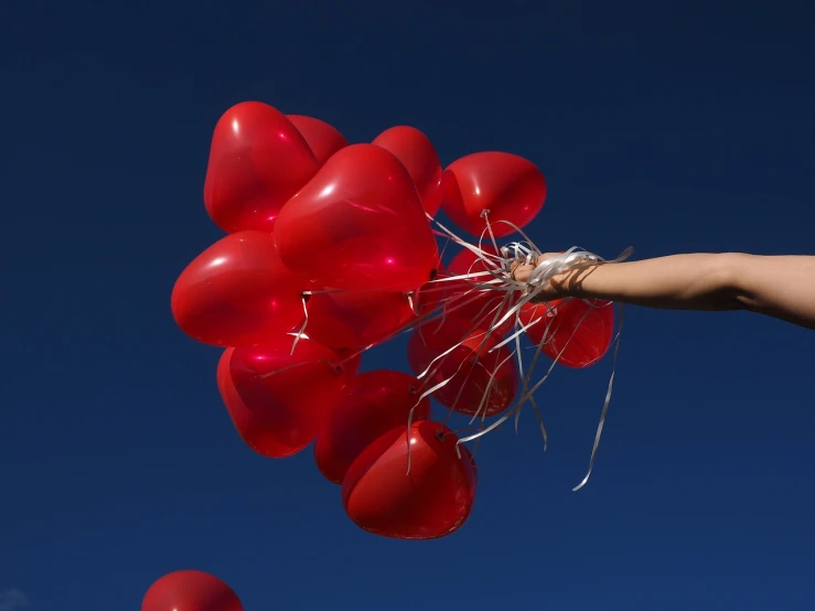 a person holding a bunch of red balloons, a picture, by Steven Belledin, blue sky, closeup of arms, heart effects, skins