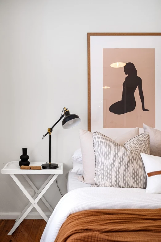 a bed room with a neatly made bed and a picture on the wall, poster art, by Sydney Carline, beautiful female body silhouette, famous designer lamp, modern studio light soft colour, black and terracotta