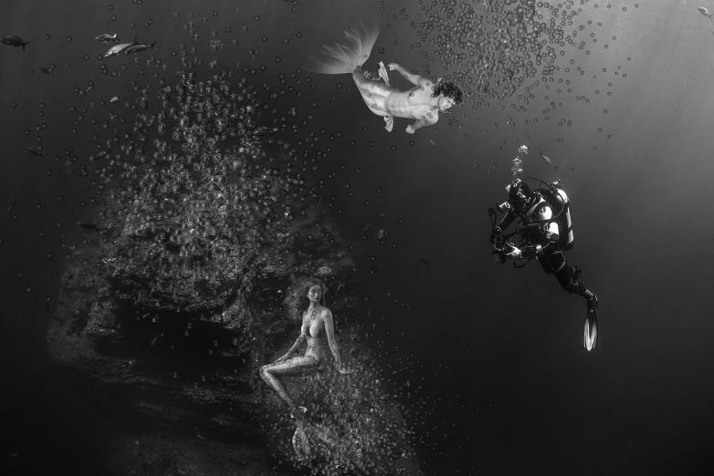 a couple of people that are swimming in the water, a black and white photo, by Robert Jacobsen, bubbly underwater scenery, mermaids and fish, angel falling to andromeda, 4 k )