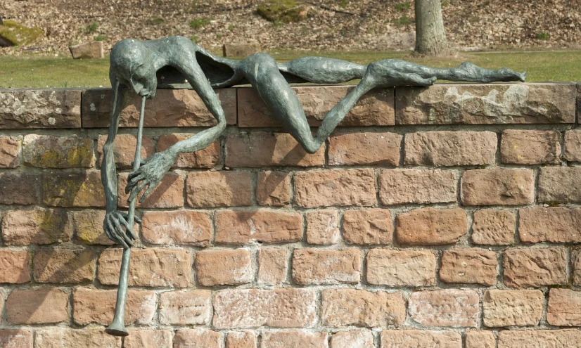 a statue sitting on top of a brick wall, a surrealist sculpture, inspired by Sir Jacob Epstein, pexels, new sculpture, swinging on a vine over a chasm, detmold charles maurice, draped with horrors and spines, detail