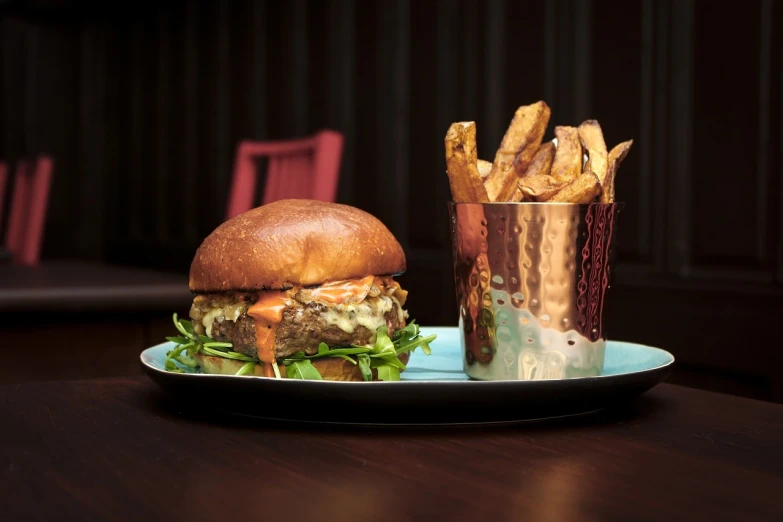 a burger and fries on a plate on a table, by Austin English, decadent, sparkling, on a dark background, spitfire