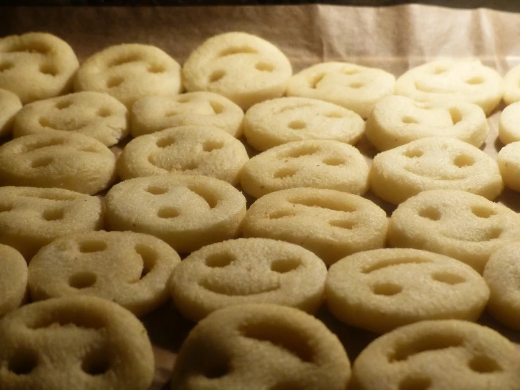 a pile of doughnuts sitting on top of a table, a portrait, inspired by Ödön Márffy, precisionism, large smile, eyes made out of macaroni, face!!!! close - up, therookies