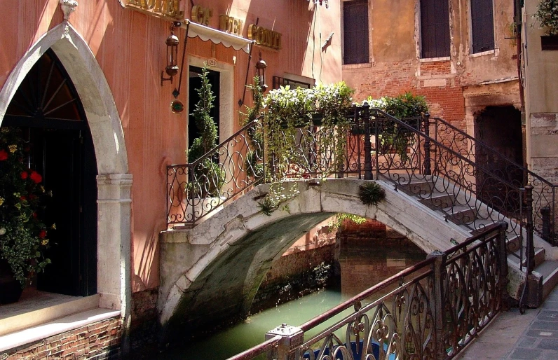 a bridge over a canal next to a building, a picture, by Rhea Carmi, flickr, olive garden, very romantic, 6 4 0, venetian red