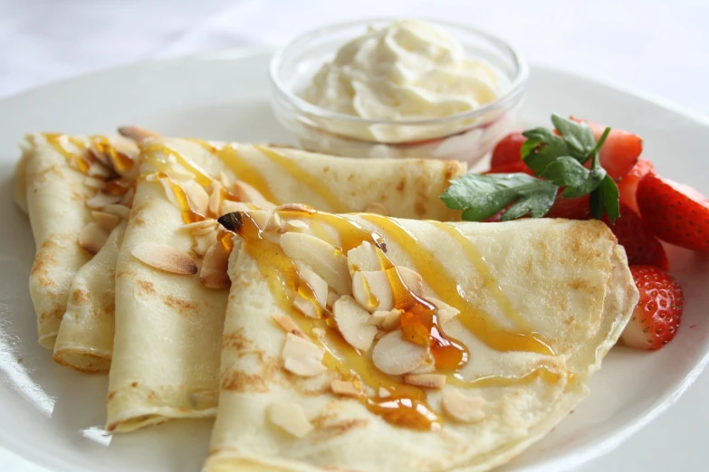 a white plate topped with crepes next to a bowl of fruit, by David Garner, flickr, maple syrup & hot fudge, blonde cream, islamic, beautiful look