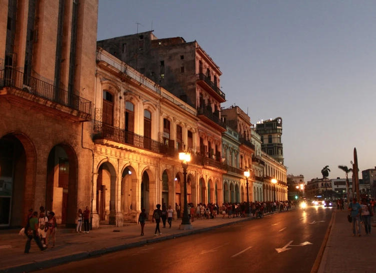 a group of people walking down a street next to tall buildings, by Matteo Pérez, flickr, renaissance, cuban setting, light above palace, in the evening, wikimedia commons