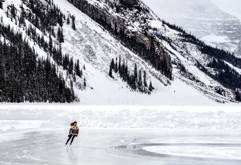 a woman riding skis down a snow covered slope, a photo, by Raymond Normand, pexels contest winner, figuration libre, icy lake setting, banff national park, sparse frozen landscape, stock photo