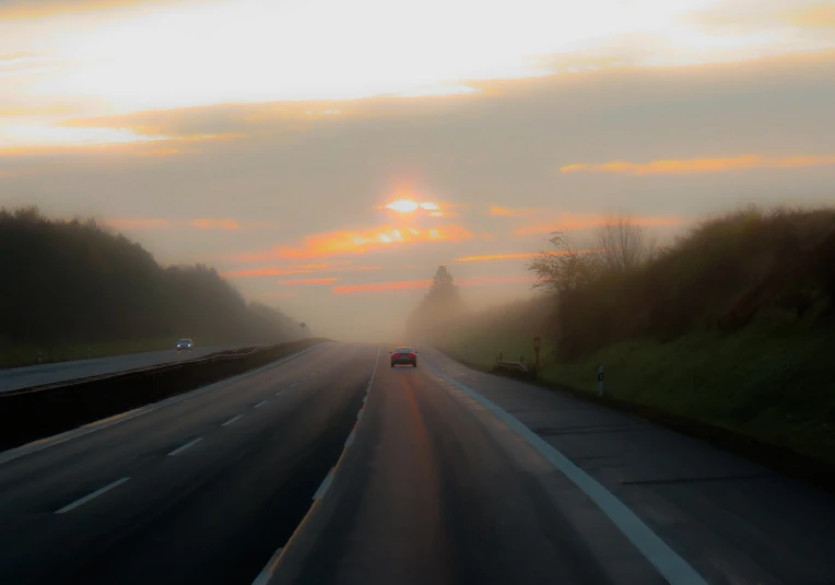 a car driving down a highway on a foggy day, by Kurt Roesch, flickr, at sunrise in springtime, sun after a storm, horizon forbideen west, oversaturated