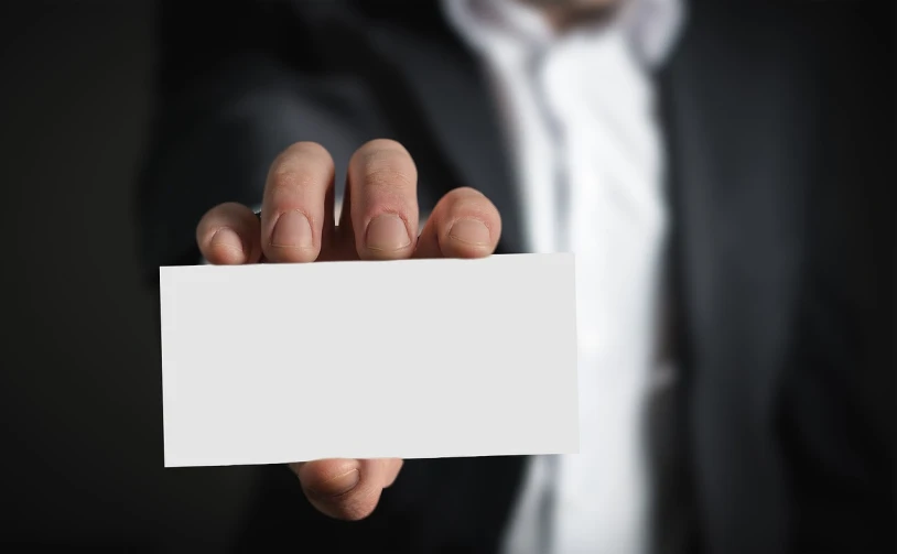 a man in a suit holding a business card, a picture, shutterstock, realism, background image, close - up photo, look what you have done, no - text no - logo