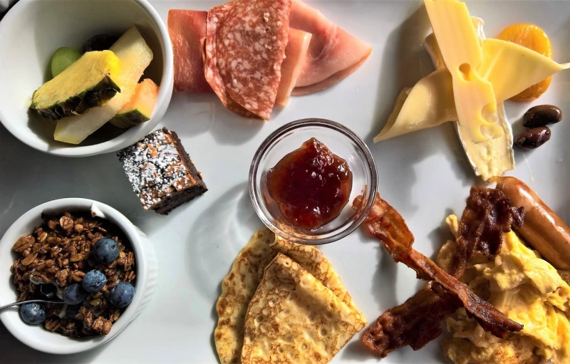 a white plate topped with different types of food, by Tom Wänerstrand, breakfast buffet, lunchmeat, boston, cheeses