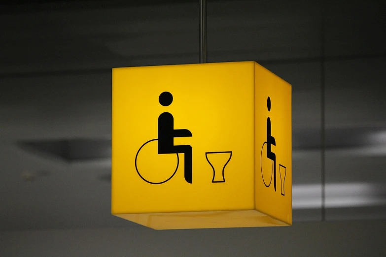 a yellow sign with a picture of a man in a wheelchair, by Matija Jama, minimalism, gaming toilet, interesting lights, wikipedia, light from bottom