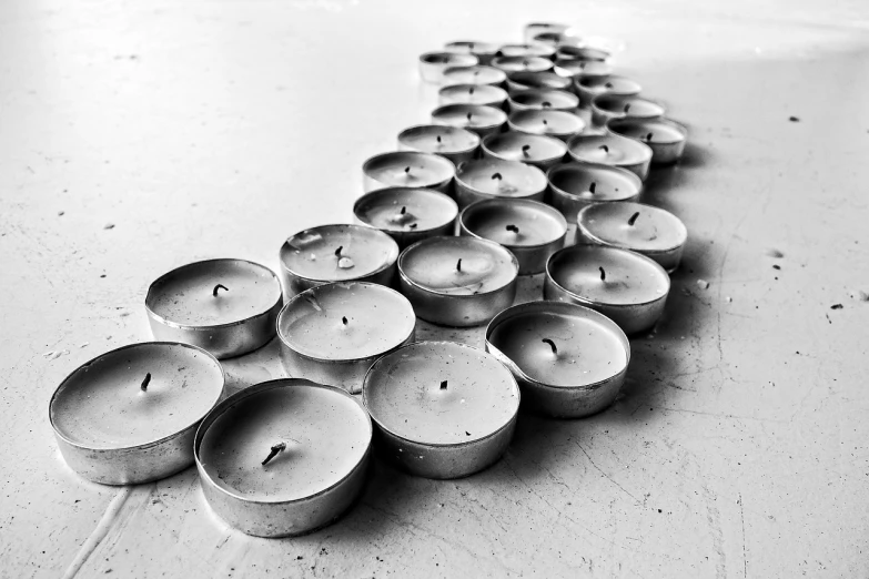 a group of candles sitting on top of a floor, a black and white photo, by Weiwei, concrete art, closeup photograph, silver lining, in a row, from the waist up