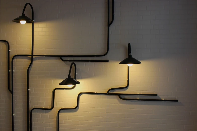 a couple of lights that are on a wall, pexels, with pipes attached to it, light bends to him, black wired cables, highly stylized