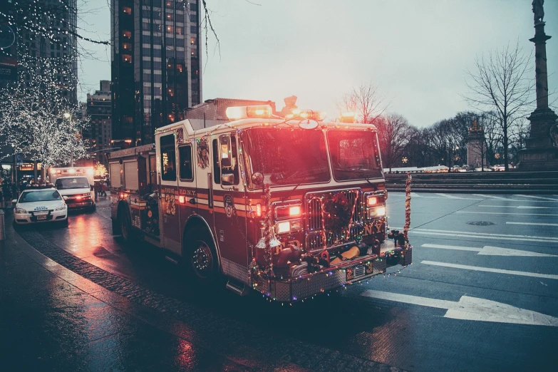 a fire truck driving down a street next to tall buildings, by Adam Rex, pexels, dazzling lights, retro effect, four legged, front shot