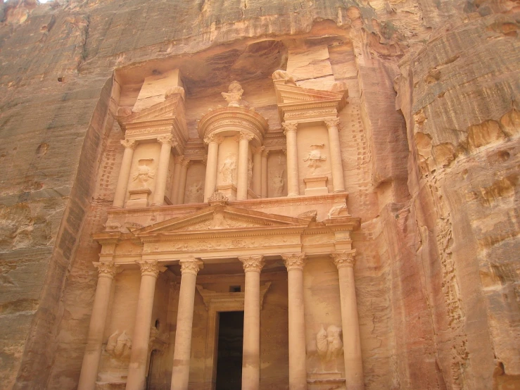 a large building built into the side of a mountain, by Ken Elias, art nouveau, jordan, roman pillars, ancient goddess, front photo