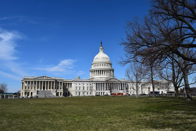 a large white building sitting on top of a lush green field, a picture, by Tom Carapic, capitol building, afp, february), sunny day