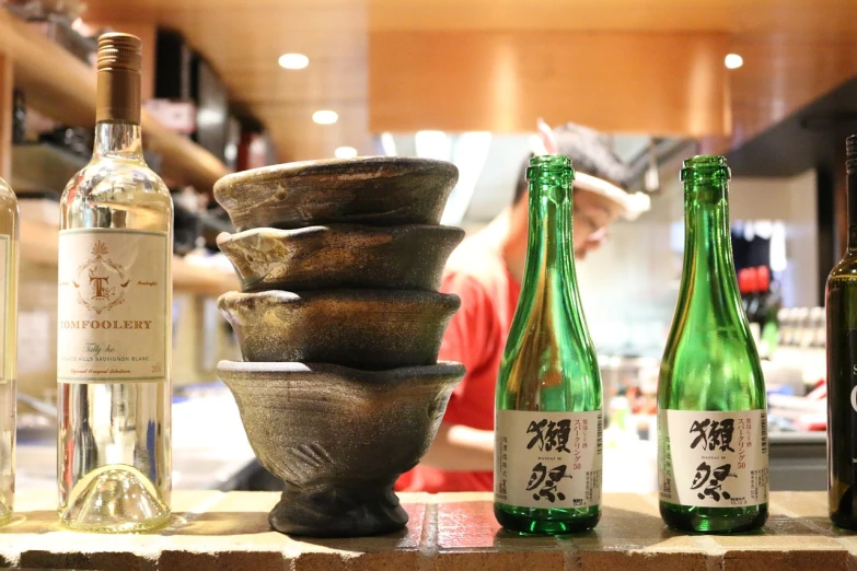 a group of wine bottles sitting on top of a counter, by Sengai, ginko showing a new mushi, traditional, tearing, sparkling water