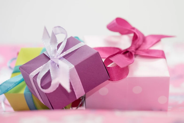 a pile of gift boxes sitting on top of a bed, by Alice Mason, pixabay, purple and pink, close up shot from the side, bowknot, ladies