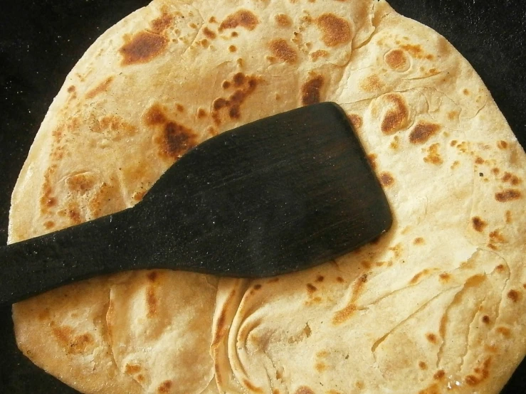 a wooden spatula sitting on top of a tortilla, flickr, hurufiyya, hindu, round-cropped, jacqueline e, hair