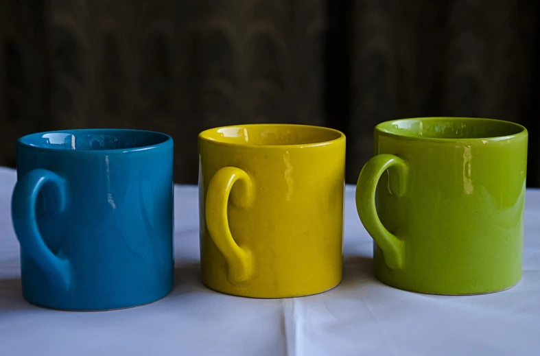 three coffee mugs sitting side by side on a table, by Doug Ohlson, flickr, vivid colors!, some yellow green and blue, highly detailed product photo, 7 0 mm photo