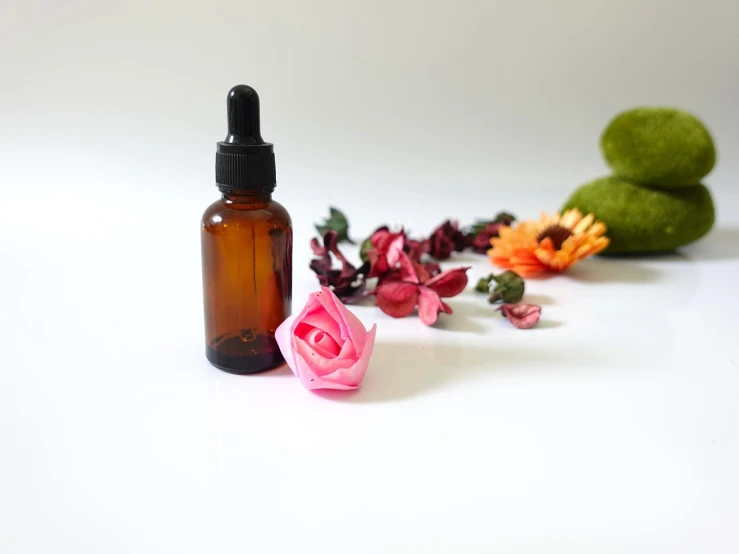 a bottle of essential oil next to a flower, a picture, 4 k product photo, amber, product photo, nipple