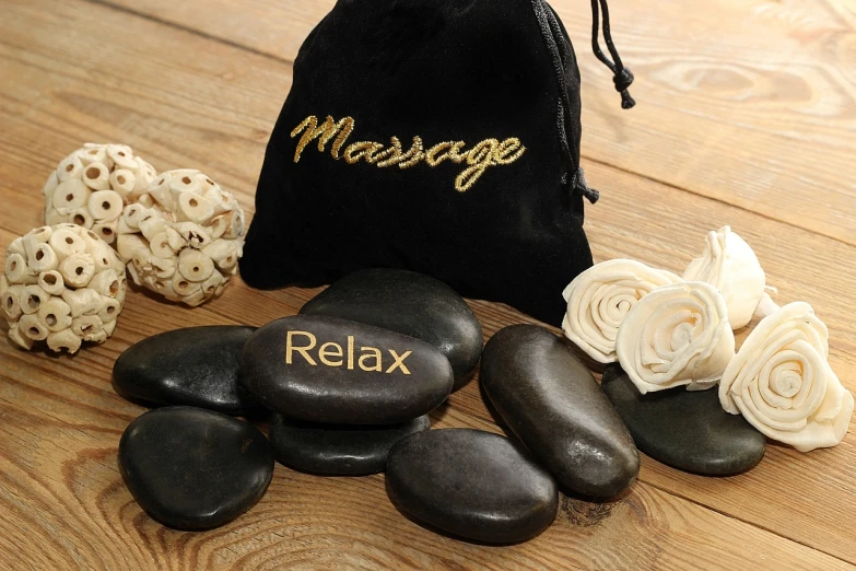 a bag of massage stones sitting on top of a wooden floor, messages, black, deluxe, 8 к