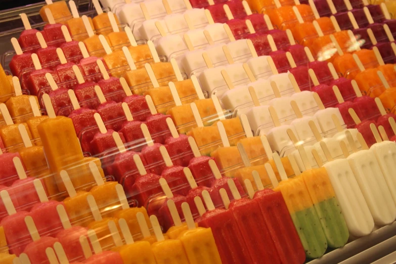 a display case filled with lots of different colored pops, a picture, by Erwin Bowien, pexels, juice, froz, yellow and red color scheme, stacked