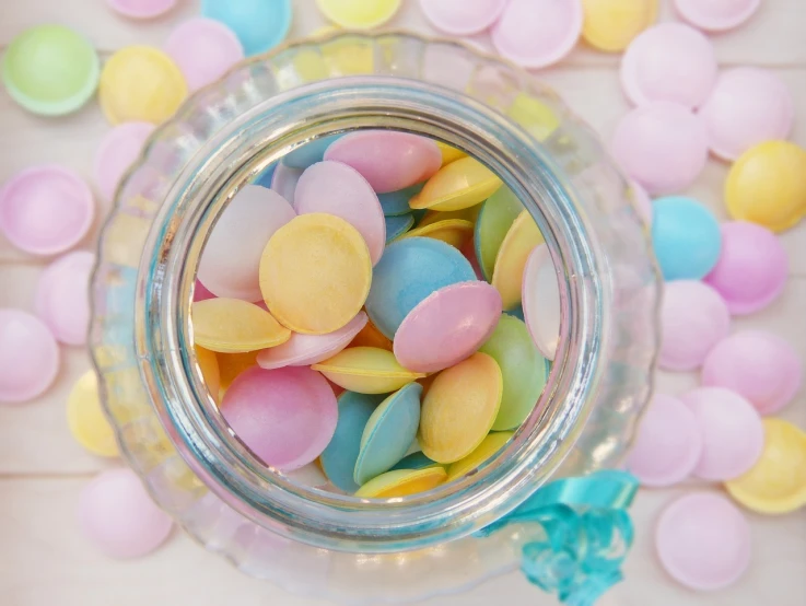 a jar filled with candy sitting on top of a table, a pastel, inspired by Peter Alexander Hay, pexels, flying saucers, pearlescent skin, photo 50mm, pastelle