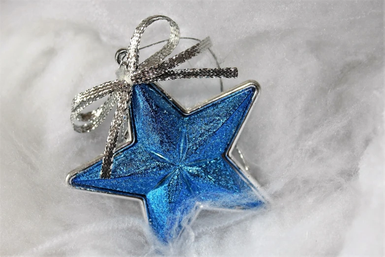 a blue star ornament sitting on top of a snow covered ground, a photo, pixabay, cloisonnism, silver background, the blue whale crystal texture, profile close-up view, product introduction photo