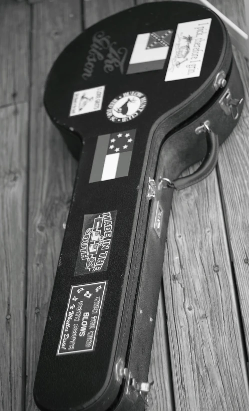 a guitar case sitting on top of a wooden floor, by Wayne England, bw photo, taken in silver dollar city, close up guns and roses, profile picture