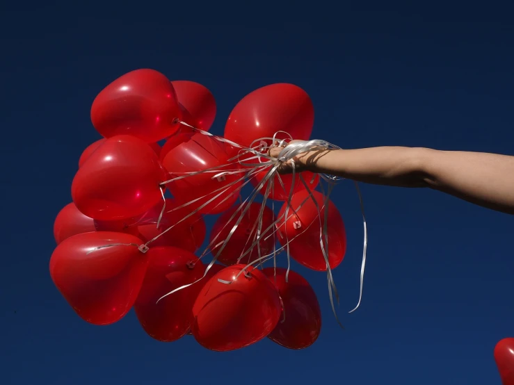 a person holding a bunch of red balloons, a picture, by Steven Belledin, hero shot, blue sky, closeup photo, skins