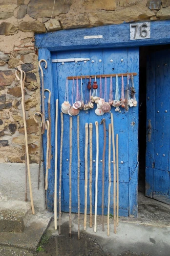 a blue door with a bunch of sticks in front of it, by François Girardon, flickr, assemblage, seashells, morocco, clubs, shepherd's crook