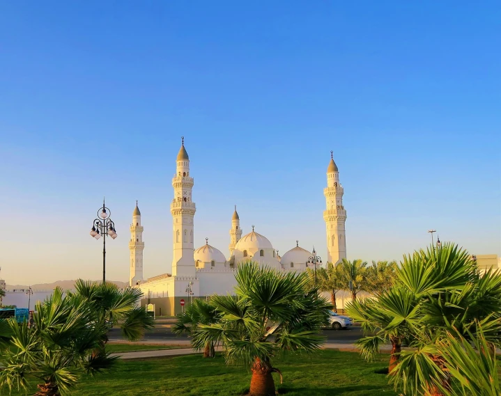 a large white building sitting on top of a lush green field, by Ahmed Yacoubi, shutterstock, dau-al-set, with beautiful mosques, date palm trees, beautiful morning, iphone photo