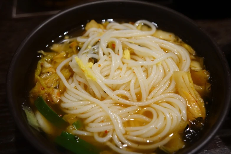 a black bowl filled with noodles and vegetables, pochi iida, medium closeup, good soup, yin zhen chu