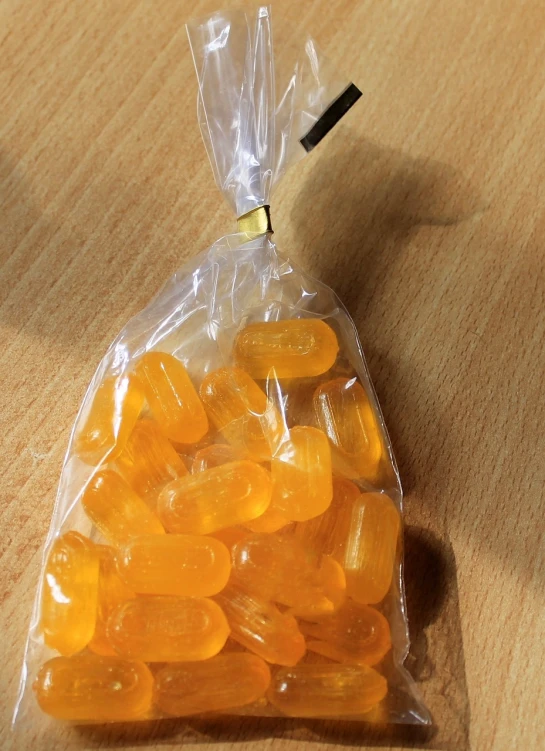 a bag of gummy bears sitting on a table, by Lisa Nankivil, reddit, hurufiyya, with a bright yellow aureola, egypt, hibernation capsule close-up, vibrant but dreary orange