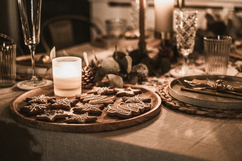 a close up of a plate of cookies on a table, a portrait, by Caroline Mytinger, pexels, room full of candles, wood ornaments, dinner is served, gingerbread people