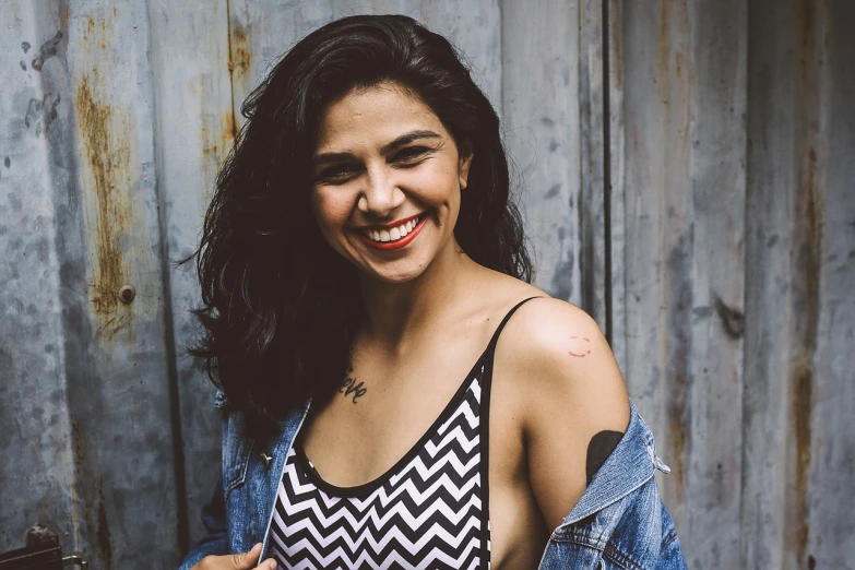 a woman is smiling while holding a cell phone, a portrait, by Amelia Peláez, tumblr, provocative indian, bralette, showing her shoulder from back, actress
