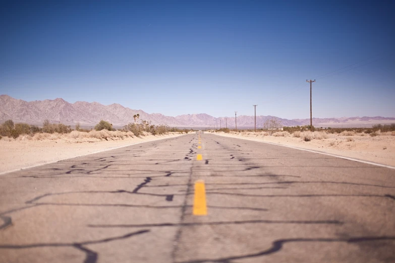 an empty road in the middle of the desert, a tilt shift photo, graffiti, usa-sep 20, low angle photo, wide shot photo, highres