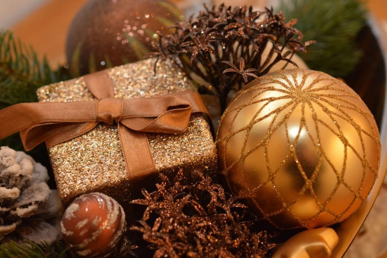 a bowl filled with christmas decorations on top of a table, a picture, by Maksimilijan Vanka, pixabay, brown and gold color palette, holding gift, closeup 4k, closeup - view