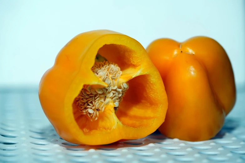 a couple of orange peppers sitting on top of a table, by Jan Rustem, one tomato slice, samson pollen, closeup photo, botanical