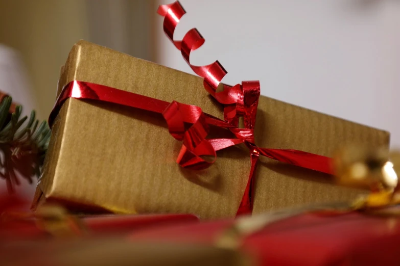 a christmas present sitting on top of a table, by Maksimilijan Vanka, pixabay, happening, red and golden color details, brown paper, close up angle, stock photo