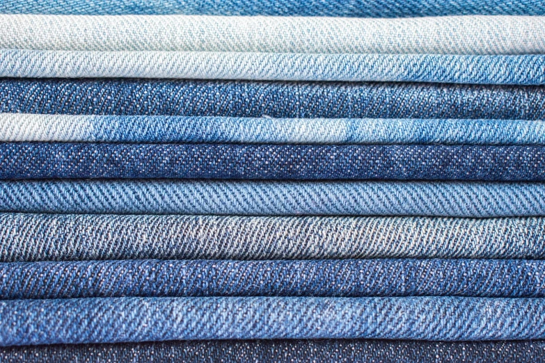 a stack of blue jeans stacked on top of each other, a stock photo, shutterstock, fine art, 8k fabric texture details, blue and white color palette, california;, on display