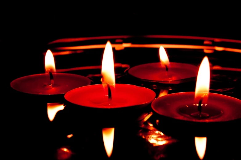 a group of lit candles sitting on top of a table, a photo, shutterstock, hurufiyya, red on black, reflection, hd wallpaper, volumetrics lights