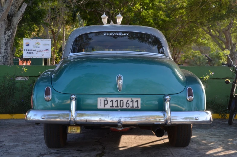 an old green car parked in a parking lot, by Juan Carlos Stekelman, flickr, rear view, cuba, back - view, underside