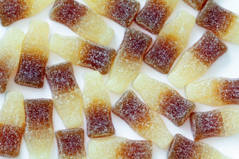 a pile of candies sitting on top of a white surface, a macro photograph, inspired by Hermann Rüdisühli, pexels, renaissance, gradient brown to white, jelly - like texture. photograph, pi - slices, hemp