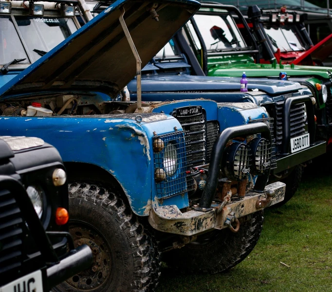 a row of old cars parked next to each other, by Richard Carline, unsplash, auto-destructive art, land rover defender, strong blue rimlit, mud, organic detail